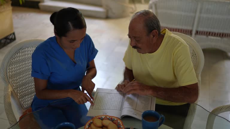 Mid adult nurse and senior man playing with crosswords at home