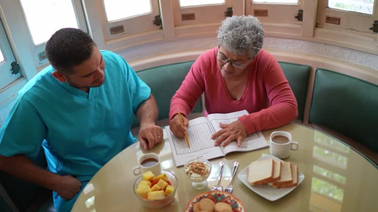 Mid adult nurse and senior woman playing with crosswords at home