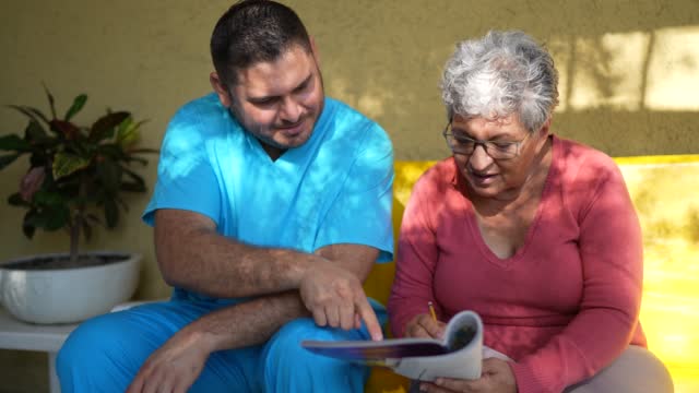 Mid adult nurse and senior woman playing with crosswords at home
