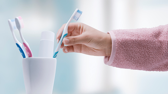 Woman taking her toothbrush in the bathroom, she is cleaning her teeth, oral hygiene concept