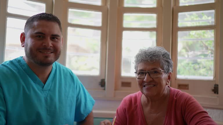 Portrait of mid adult nurse and senior woman playing with crosswords at home