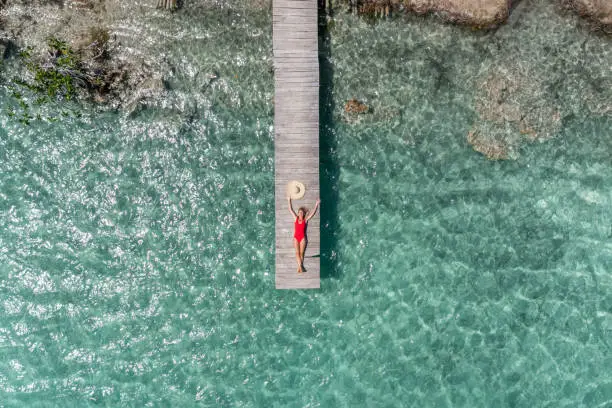 Photo of Drone view of woman relaxing on pier above lagoon