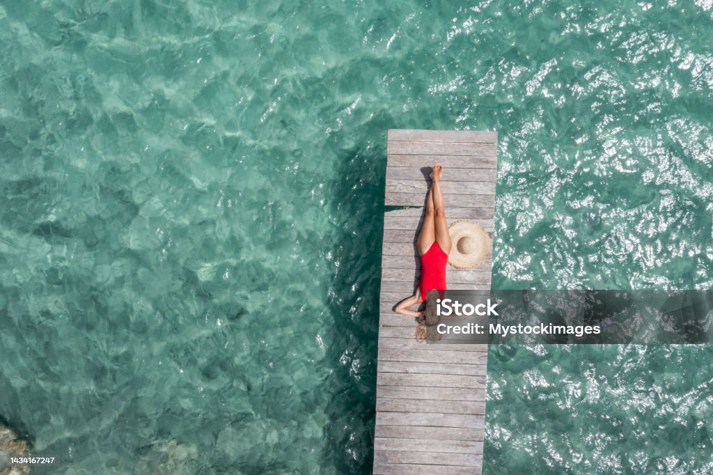 Drone view of woman relaxing on pier above lagoon 30's woman relaxes in nature on the beautiful lake of Bacalar, Mexico Women Stock Photo