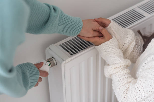 istock Child warming hands on heating radiator near white wall, closeup 1434167647