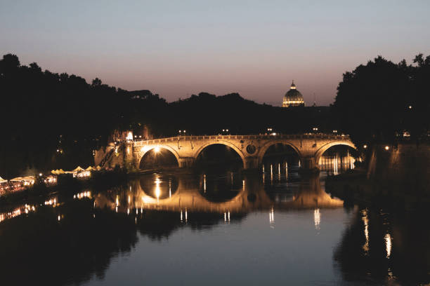 most ponte sisto w rzymie nad tybrem w nocy. jest ładnie oświetlony w nocy, aw oddali widoczna jest bazylika. nad rzeką znajduje się targ. - riverside night reflection italy zdjęcia i obrazy z banku zdjęć