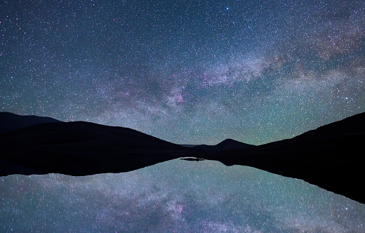 Beautiful night landscape. Mountains and small under bright milky way galaxy. Starry night.