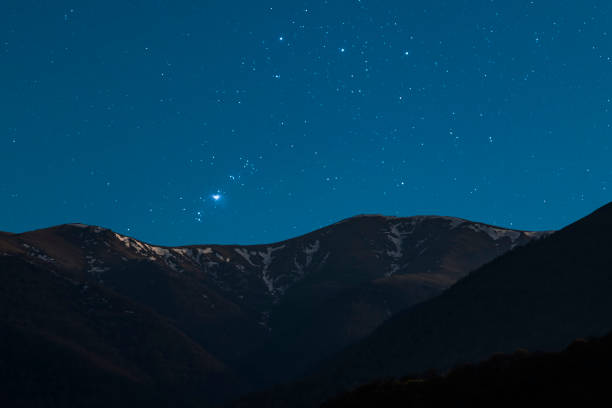 istock Beautiful night landscape. Snow covered mountains under starry sky with orion galaxy. 1434169032