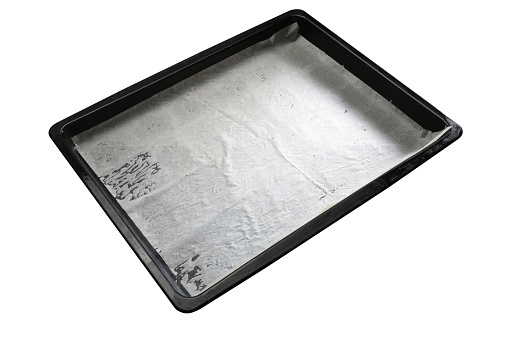 Empty baking sheet with wax paper isolated on the white background with clipping path