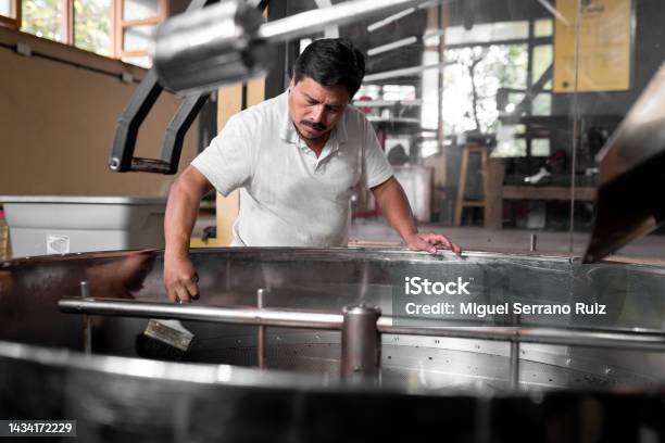 An Hispanic Man Is Cleaning The Coffee Roaster Machine Cooling Tray Stock Photo - Download Image Now