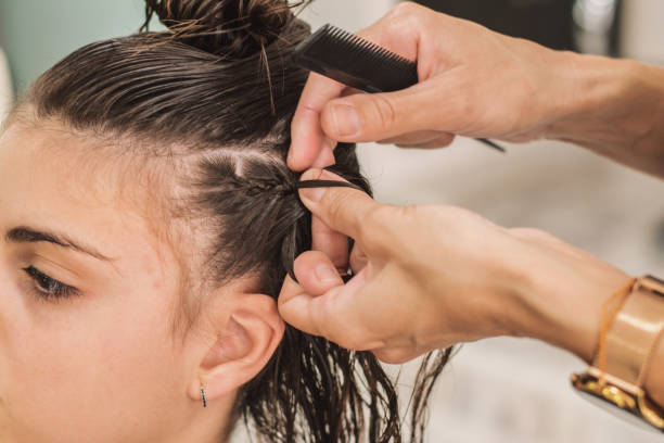 Beauty salon. Hairdresser Close-Up Of A Young Woman With A Braided Hair Extension In A Beauty Salon, Real Life. Woman at the hairdresser. Hairdresser while working. short weave hairstyles stock pictures, royalty-free photos & images