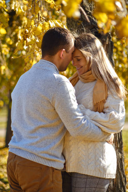 pregnant woman and man posing at autumn park - human pregnancy couple prenatal care heterosexual couple imagens e fotografias de stock