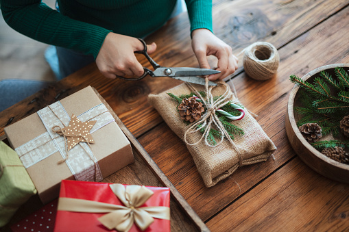 Woman preparing christmas gift in rustic style with zero waste materieals.