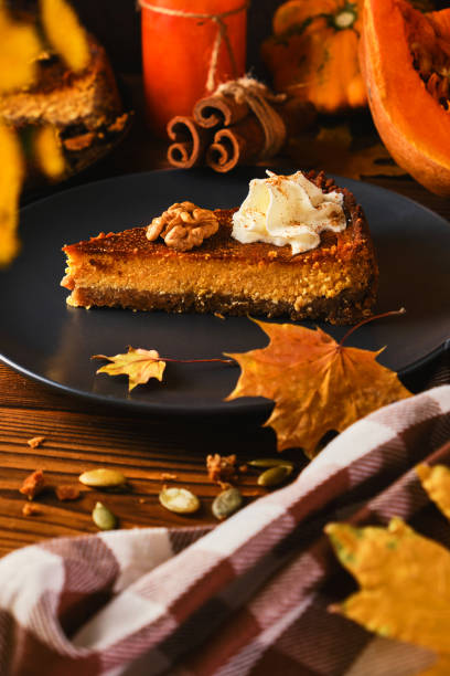 Homemade pumpkin cheesecake decorated with whipped cream on black plate made for Thanksgiving. The toning. selective focus