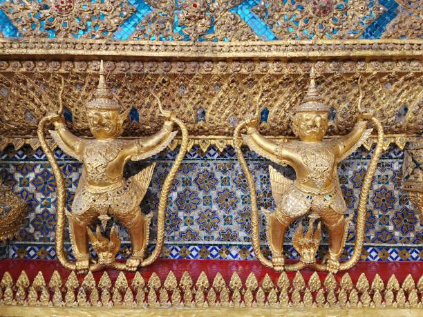 garuda cattura la statua naga allineata attorno alla base del muro esterno intorno all'ubosot di wat phra kaew - wat thailand demon tourism foto e immagini stock