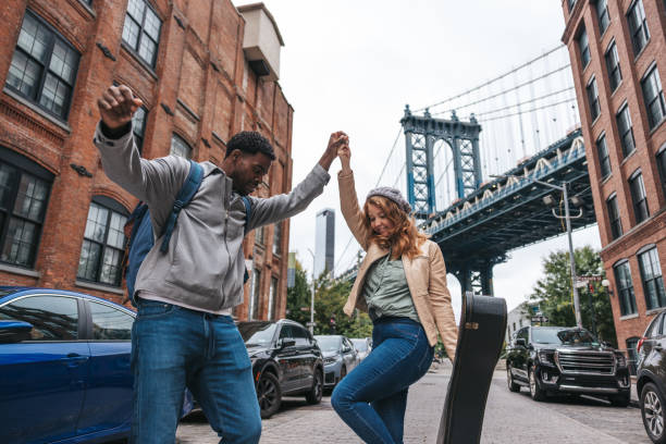 Happy couple enjoying a vacation in New York Happy mixed couple discovering New York City for the first time. They are walking in Dumbo next to Manhattan and Brooklyn Bridge. tourist couple candid travel stock pictures, royalty-free photos & images