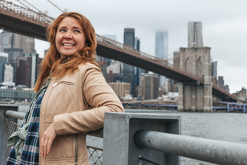 Happy person posing next to Brooklyn Bridge for a few portraits with Manhattan skyline on the background.