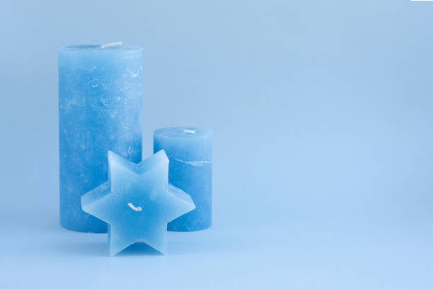 Set of blue wax candles for interior design on a blue background. Minimalistic and beautiful accessories. Idea for cold winter gift and decorating home, cafe, shop. Relax and meditation atmosphere