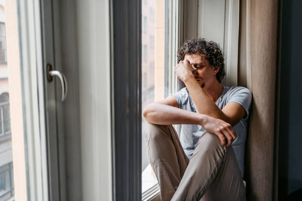istock Depressed Young Man Sitting By The Window 1434189212