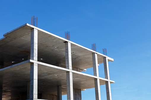 Reinforced concrete frame of a building under construction against a blue sky background