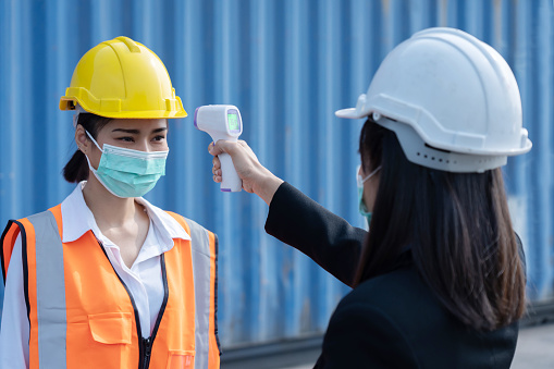 Asian Manager Checking Engineer Worker Body Temperature For Covid19 Virus with Infrared Thermometer Gun at the Working Site