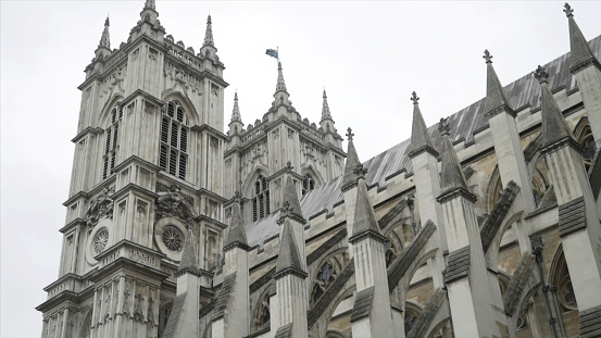 View from the bottom on the Westminster Abbey exterior details against the grey cloudy sky. It is a large, mainly Gothic abbey church in the City of Westminster, London