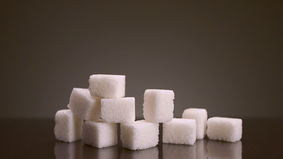 Pile of sugar cubes on isolated background. Stock footage. Pile of sugar cubes changes in number on isolated background. Sweets in large quantities are harmful to health. Sugar and sweets are 21st century addiction.