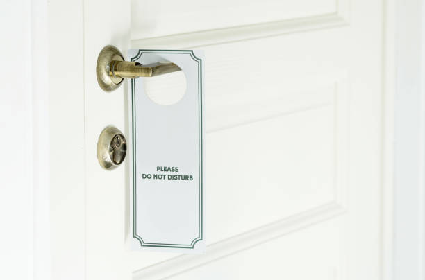 istock Closed white hotel room door with white please do not disturb sign on chrome handle. 1434193113