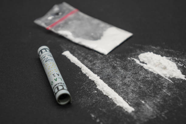 anfetamina divisa in una traccia su un tavolo nero. polvere bianca narcotica ravvicinata. - anfetamine foto e immagini stock