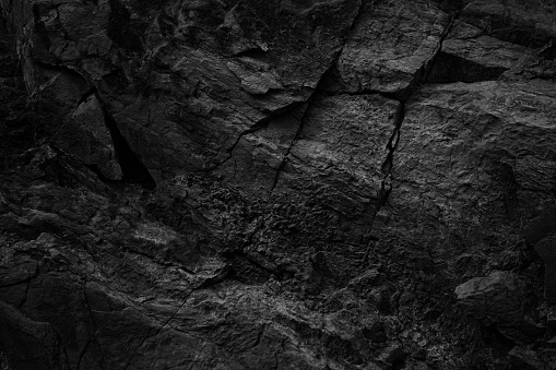 Black white rock texture with cracks. Rough surface mountain surface. Close-up. Dark grey. Stone granite background with space for design. Grunge. Broken.