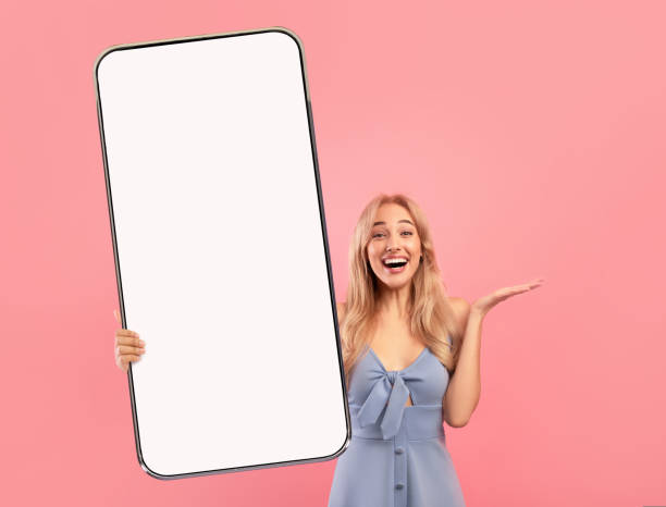 istock Check out this new app. Overjoyed pretty lady presenting smartphone with white empty screen, mockup for your design 1434195557