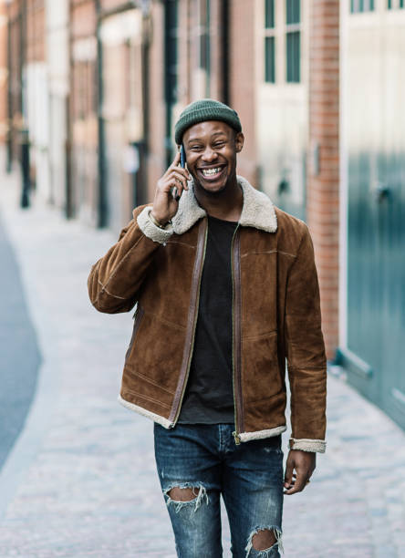 African man talking on the phone and walking down the street stock photo