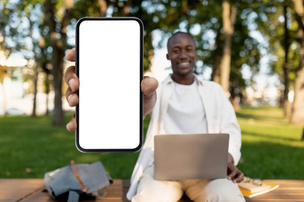 istock African american student guy demonstrating big blank smartphone while studying outdoors with laptop, mockup 1434197923