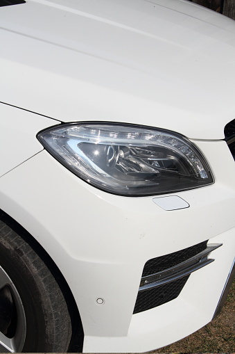 A modern car headlight with daytime running lights on a white car