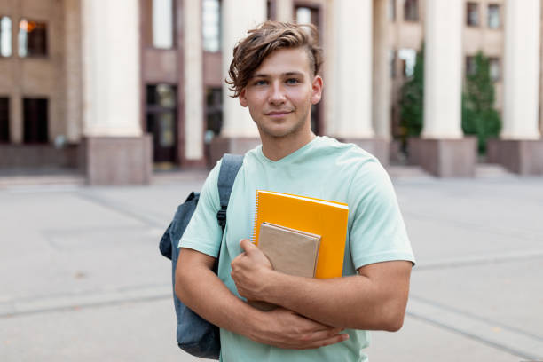 istock Portraif of happy student guy with backpack and workbooks posing over university building background 1434199443