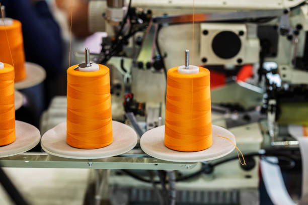Spools with orange threads on sewing machine. Sewing Equipment, Fabric and Textile Industry