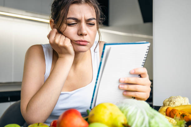 istock A young woman in the kitchen with a notebook among vegetables. 1434204302
