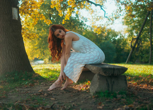 Young woman posing on the bench by the tree.