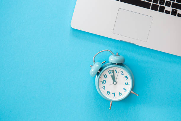istock Alarm clock and laptop on a blue background, flat lay. 1434209105