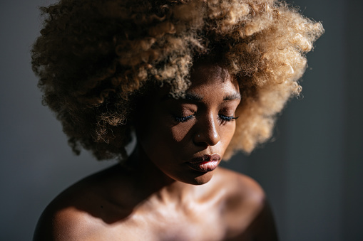 Studio shot of serious African-American woman with clean skin and curly hair.