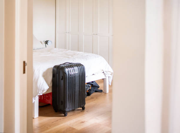 istock Packed suitcase with wheels standing next to a bed 1434211248