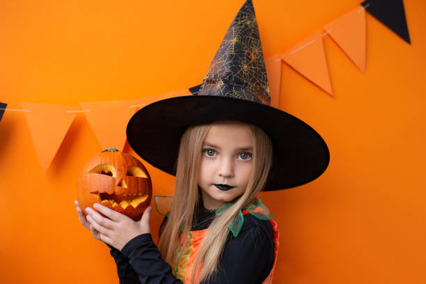 istock Happy Halloween! Cute little witch with a pumpkin 1434211931