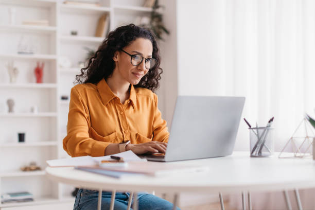 kobieta z bliskiego wschodu korzystająca z laptopa pracująca online siedząca w biurze - biurko zdjęcia i obrazy z banku zdjęć