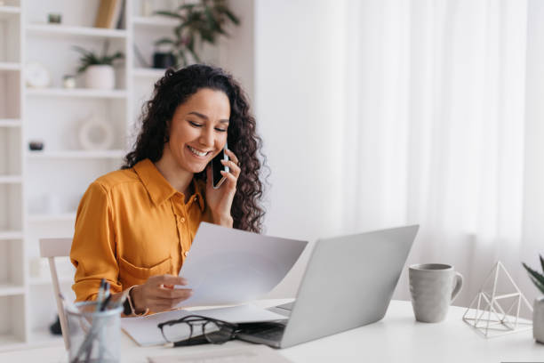 istock Middle Eastern Woman Talking On Smartphone Holding Paper At Workplace 1434212363