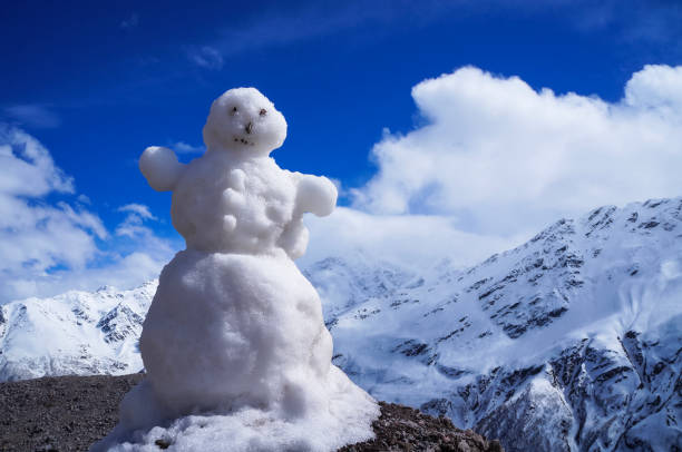 istock White snowman in mountains against blue sky in a bright winter day 1434214362
