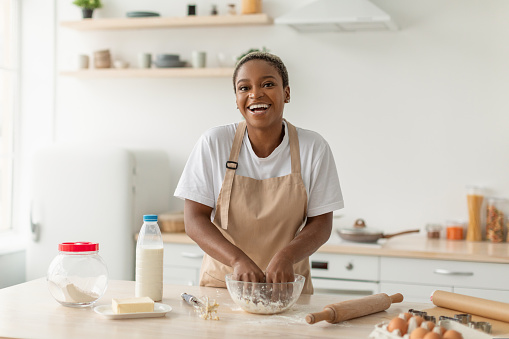 istock Laughing young african american lady in apron making pie dough in minimalist kitchen interior 1434215267