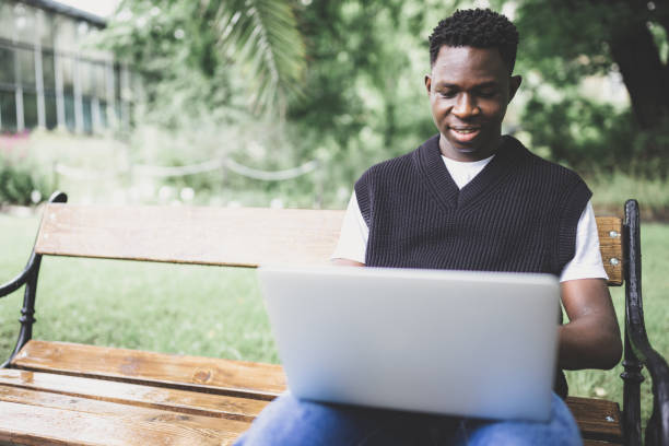 istock Young black man working on laptop outdoors, looking at screen, smiling 1434216859