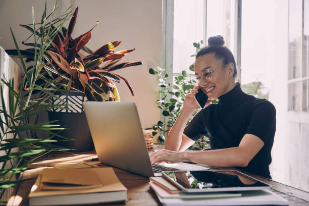 istock Happy young woman talking on mobile phone while working in the office 1434217229