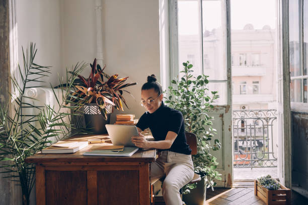 istock Concentrated young woman using digital tablet while sitting at her working place in office 1434218216