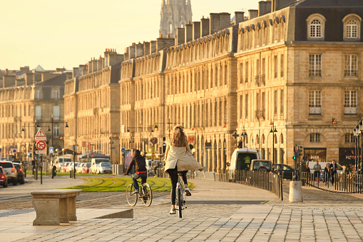 Bordeaux, France - 19 March, 2020 : Selective focus on woman on bicycle  at Place de la Bourse with St. Michel church on the back