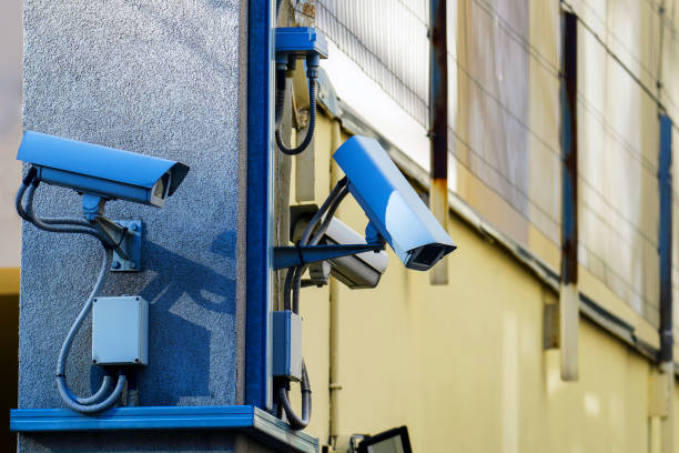 Three surveillance cameras on a concrete pole are directed in different directions